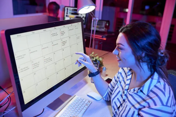 Młoda Uśmiechnięta Bizneswoman Siedząca Przy Stole Wskazując Monitor Komputera Przygotowuje — Zdjęcie stockowe