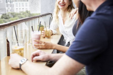 Kafede lezzetli içecekler konuşan ve içen mutlu genç arkadaşlar grubu