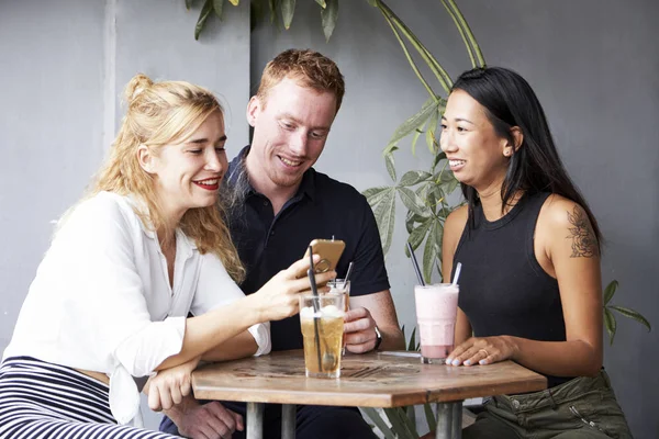 Gruppe Von Freunden Sitzt Cafétisch Und Betrachtet Fotos Smartphone — Stockfoto