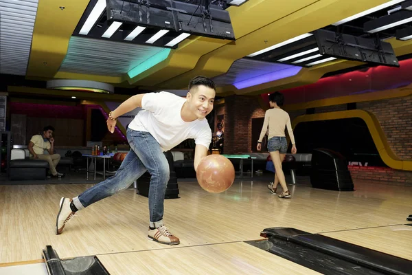 Vrolijke Jonge Vietnamese Man Die Bal Een Bowlingbaan Gooit — Stockfoto
