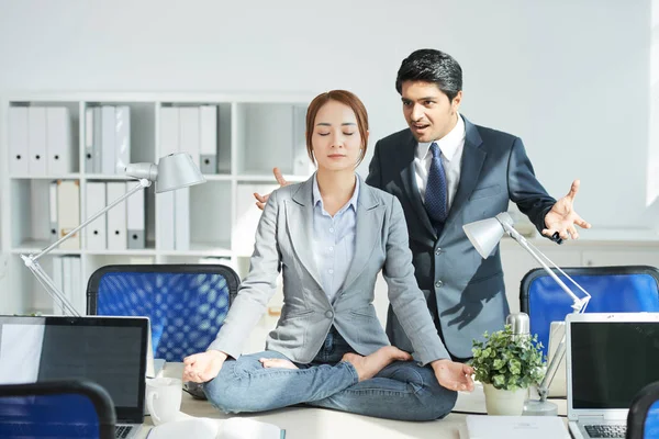 Irritated Angry Businessman Looking Young Woman Meditating Lotus Position — Stock Photo, Image