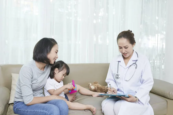 女医生坐在一张小瓦的身上 给家人开药 向母亲解释她女儿的治疗方式 — 图库照片