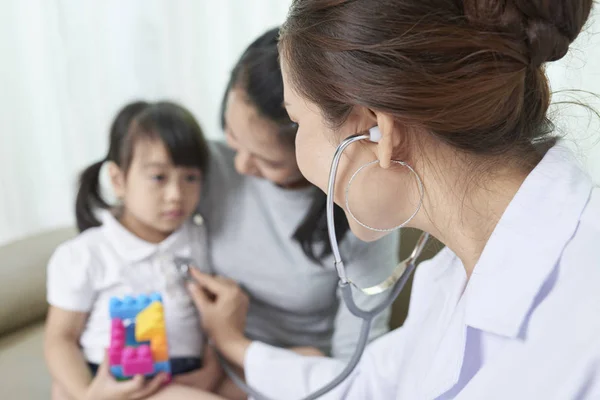 医師のオフィスでの訪問中に小さな女の子を検査聴診を持つ女性医師 — ストック写真