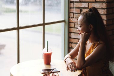 Neşeli dalgın kadın kafede taze yüzlü zevk ve pencereden bakarak