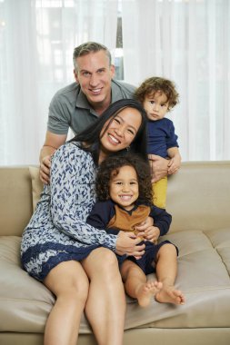 Mutlu anne, baba ve iki çocuğu evde birlikte oynuyorlar.