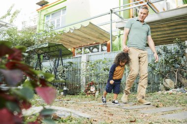 Onlar açık havada yürürken oğlunun elini tutarak Mutlu olgun baba