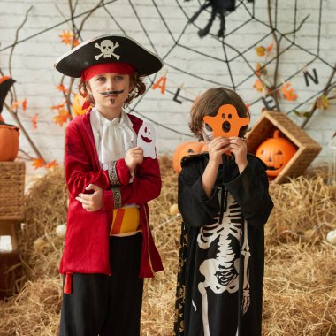 Parlak Cadılar Bayramı kostümleri içinde iki kardeş onlar kağıt kesip hayaletler ile poz