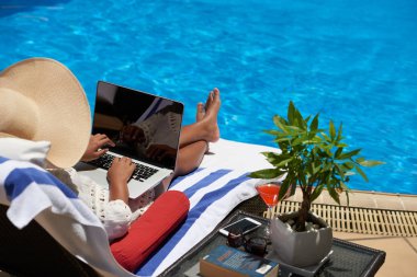 Yüzme havuzunda dinlenirken dizüstü bilgisayar üzerinde çalışan iş kadını