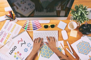 Ofisinde bilgisayar üzerinde çalışan grafik tasarımcı, yukarıdan görünümü