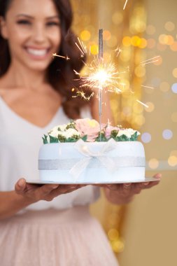 Gülen mutlu kadının ellerinde Kıvılcımlarla süslenmiş doğum günü pastası