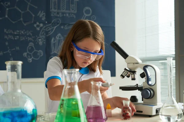Kimya sınıfında reaktifler ile çalışırken koruyucu gözlük takan küçük kız