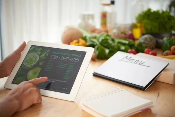 Woman reading recipe on digital tablet when composing menu