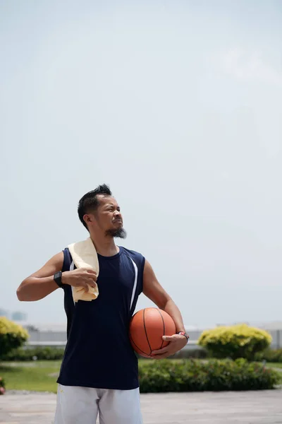 晴れた日に屋外に立ってバスケットボールボールとタオルを持つひげを生やしたフィリピン人男性 — ストック写真