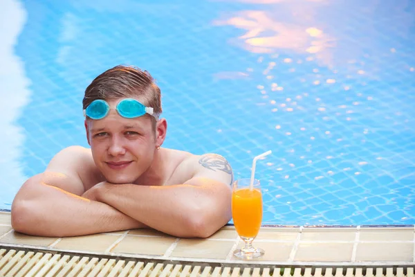 Pohledný Mladý Muž Který Opírá Okraj Bazénu Tropickým Koktejlem — Stock fotografie