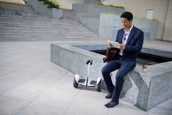 Junger Asiatischer Geschäftsmann Sitzt Brunnen Und Liest Informationen Auf Einem — Stockfoto