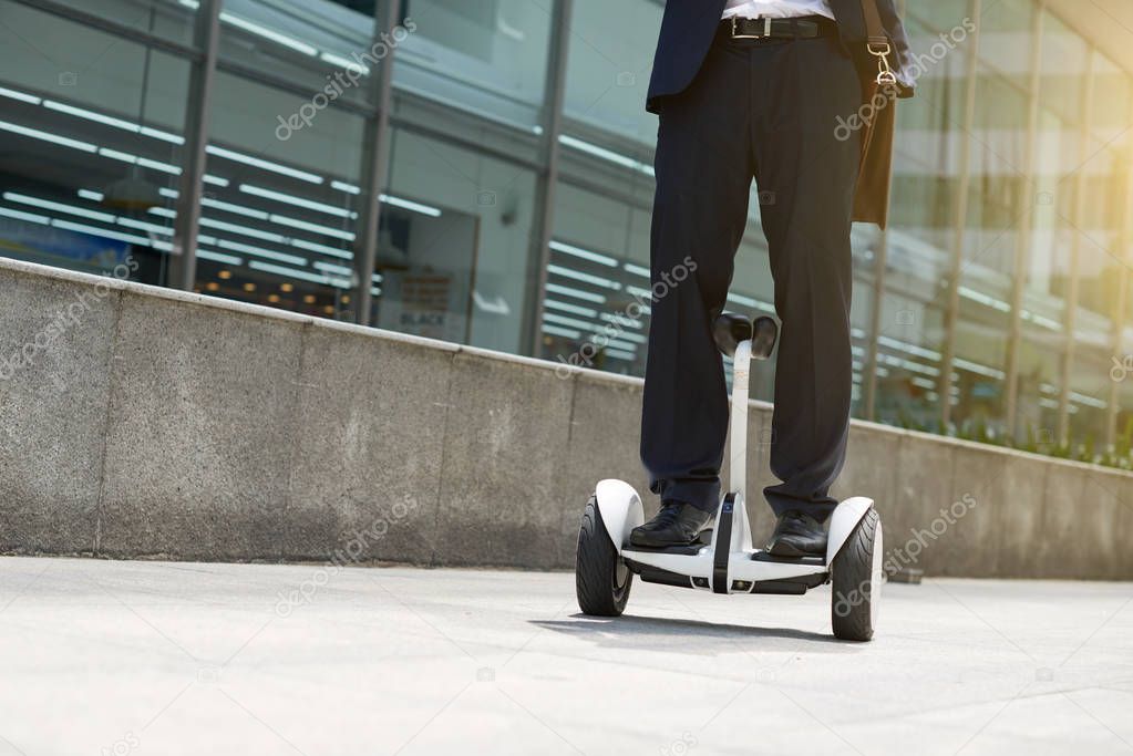 Legs of business executive riding hoverboard along the city street