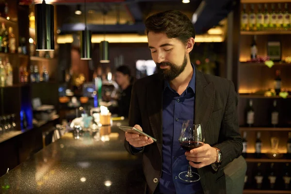 Sonriente Hombre Barbudo Bebiendo Vino Tinto Restaurante Enviando Mensajes Texto —  Fotos de Stock