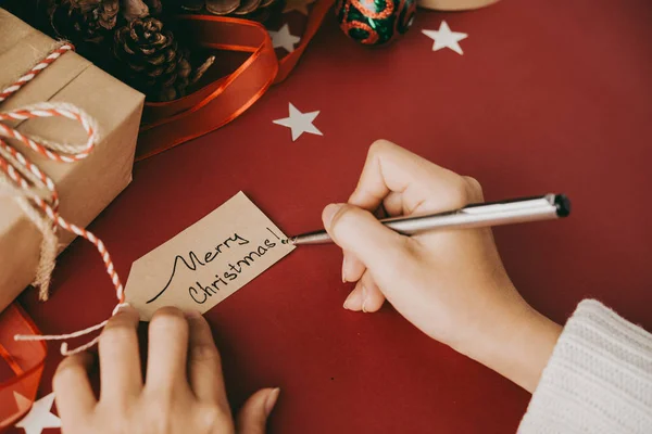 Noel Hediyeleri Hazırlarken Kırmızı Bezle Masada Oturan Etikete Noel Dileği — Stok fotoğraf