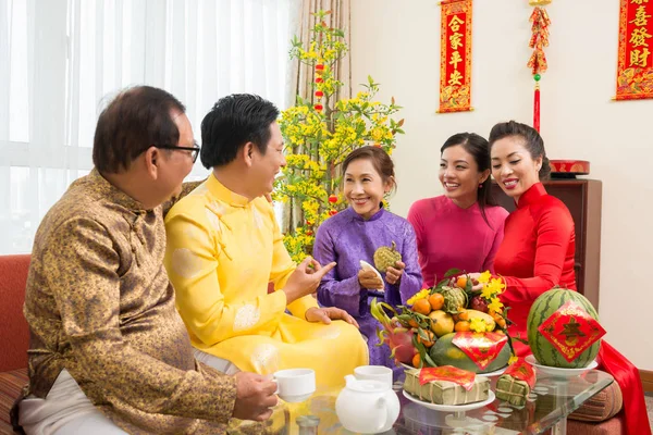 幸せなアジアの家族は バックグラウンドで来年のための最高の願いを持つカップルと自宅で中国の新年のお祝いで新鮮な果物を楽しんでいます — ストック写真