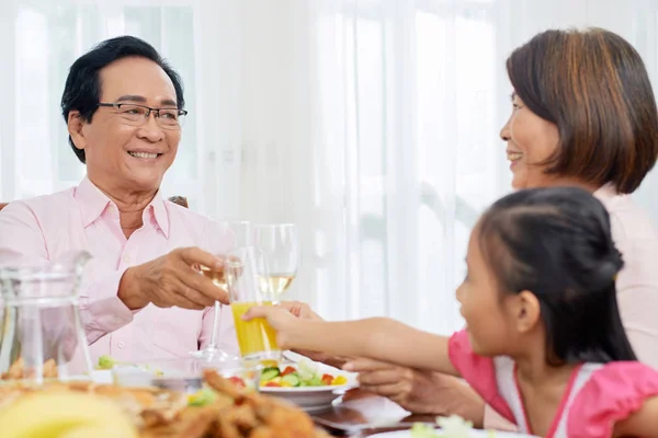 成年亚洲男人和女人与女孩在餐桌上的家庭晚餐闪烁与眼镜共度时光 — 图库照片