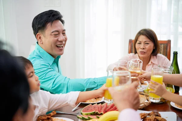 Happy Asian family with glasses toasting while having celebration at home gathering at dinner