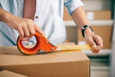 Karton kutulara yapışkan bant uygulayan post işçinin yakın çekim görüntüsü