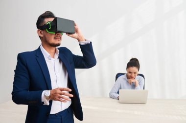 Onun iş arkadaşı sanal gerçeklik uygulaması test ederken Dizüstü çalışan Vietnamlı iş kadını