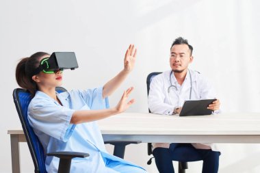 Sanal gerçeklik kulaklık kadın hasta bakarak dijital tablet ile Vietnamlı sağlık çalışanı