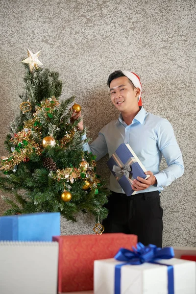 Freudiger Vietnamesischer Geschäftsmann Mit Weihnachtsmütze Schmückt Weihnachtsbaum Büro — Stockfoto