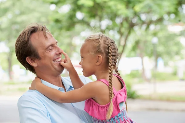 小女孩指着她快乐的父亲的鼻子 当他们在公园里休息 — 图库照片