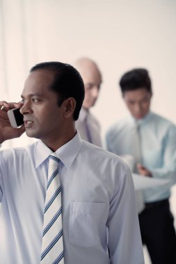 Başarılı Hintli işadamı telefonla arıyor, meslektaşları arka planda konuşuyor