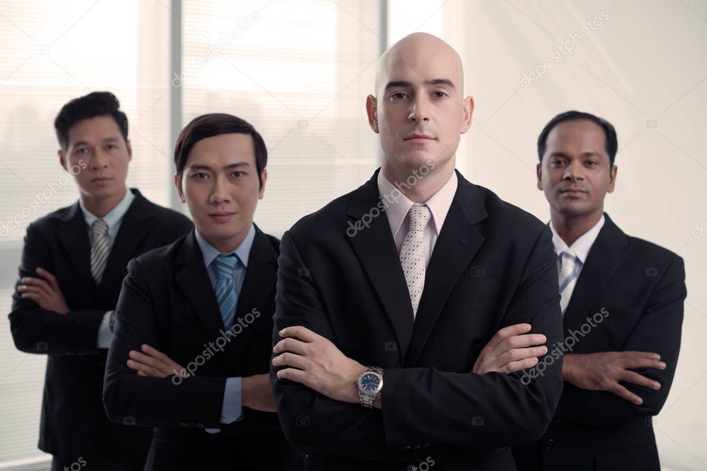 Handsome bald man standing in front of his multi-ethnic coworkers