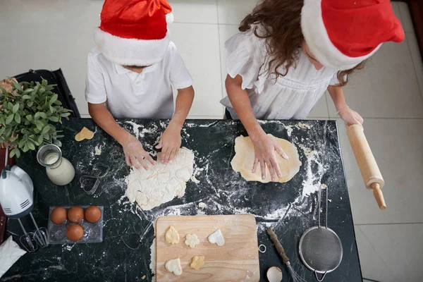 Children rolling out dough and making cookies