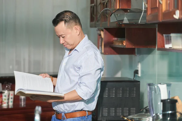 Young Man Standing His Modern Kitchen Looking Recipe Cookbook — Stock Photo, Image