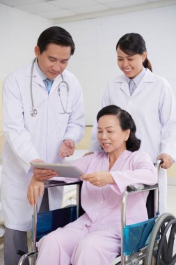 Neşeli yaşlı kadın dijital tablet doktor reçete okuma 