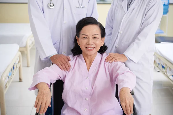 車椅子で幸せな笑顔のアジアの女性 彼女の医者が後ろに立って — ストック写真