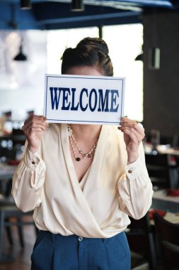 Başarılı kadın restoran sahibi hoş geldin tabelası gösteren 
