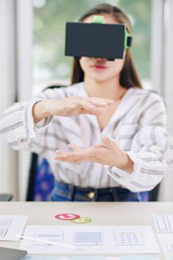 Ofis masasında VR kulaklıkta çalışan yeni uygulama tasarımı oluşturan modern kadın