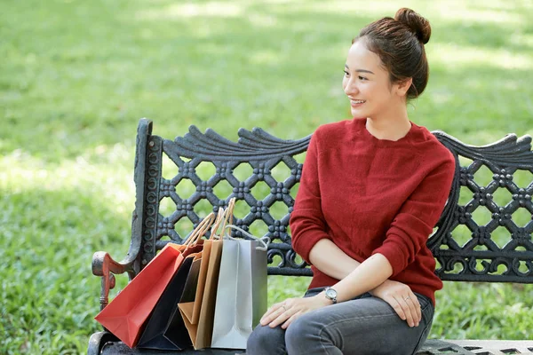 漂亮的年轻越南女人坐在长椅上 旁边有购物袋 — 图库照片
