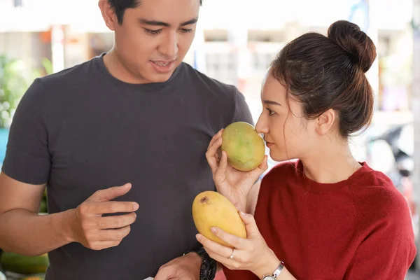 若いベトナムのカップルはマンゴーの匂いを嗅ぎ 熟したものを探しています — ストック写真