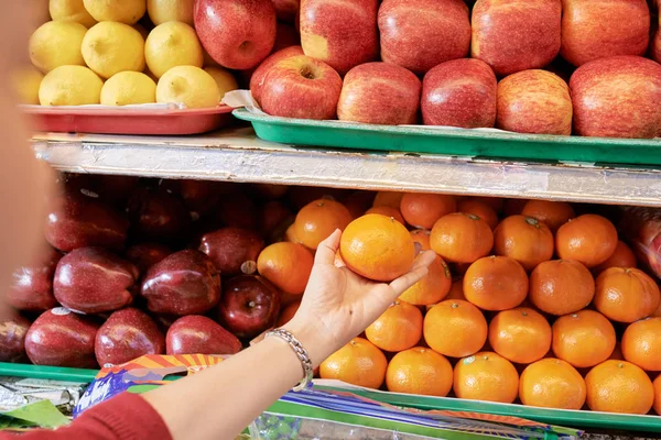 女顾客从超市货架上拿成熟的橘子的手 — 图库照片