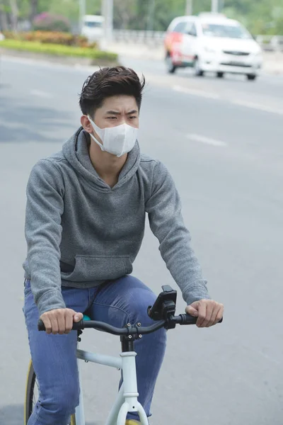骑自行车的年轻人戴着面罩保护自己免受病毒 — 图库照片