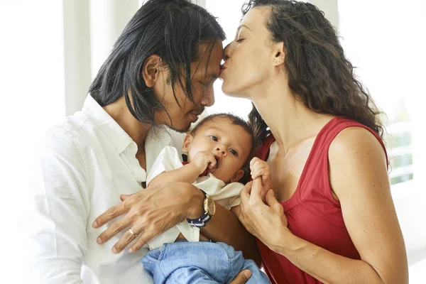 Young Beautiful Woman Kissing Her Husband While Holding Baby Boy — Stock Photo, Image