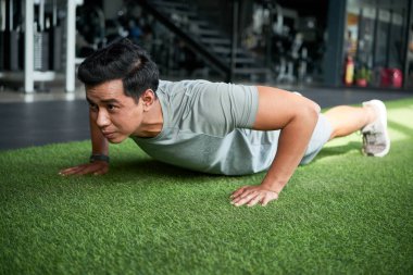 Genç erkek atlet spor salonunda yerde itme yapıyor