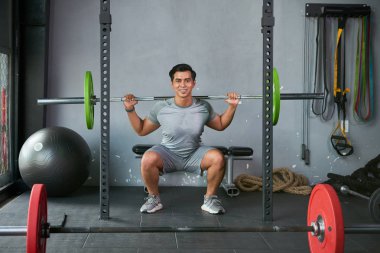 Belde de barbell ile egzersizler yapıyor jimnastikte çalışan kaslı gülümseyen adam Portresi