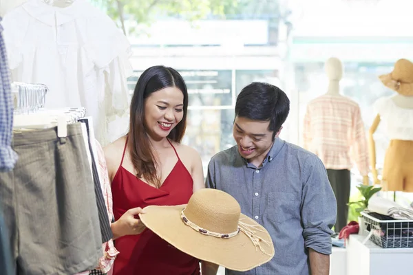 微笑的年轻亚洲妇女展示她的男朋友草帽 并征求意见 — 图库照片