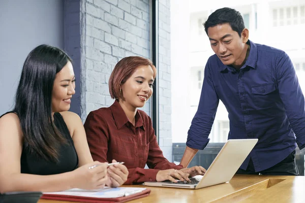 Duas Mulheres Negócios Sentadas Mesa Digitando Laptop Enquanto Líder Masculino — Fotografia de Stock