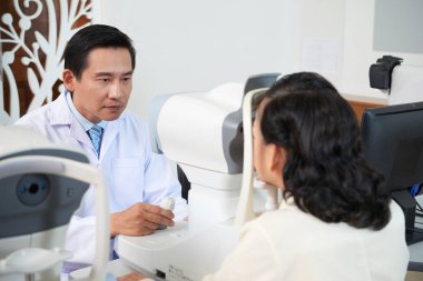 Profesyonel optometrist modern oftalmoloji kliniğinde özel ekipman kullanarak onun kadın hasta muayene