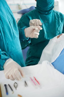 Hastayı ameliyathanede masada çalıştırmak için tıbbi aletler kullanan üniformalı ve koruyucu eldivenli cerrahların yakın çekim 