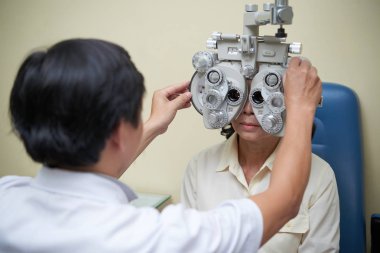 Olgun kadın fotometre ile bakıyor ve oftalmoloji kliniğinde görme kontrol
